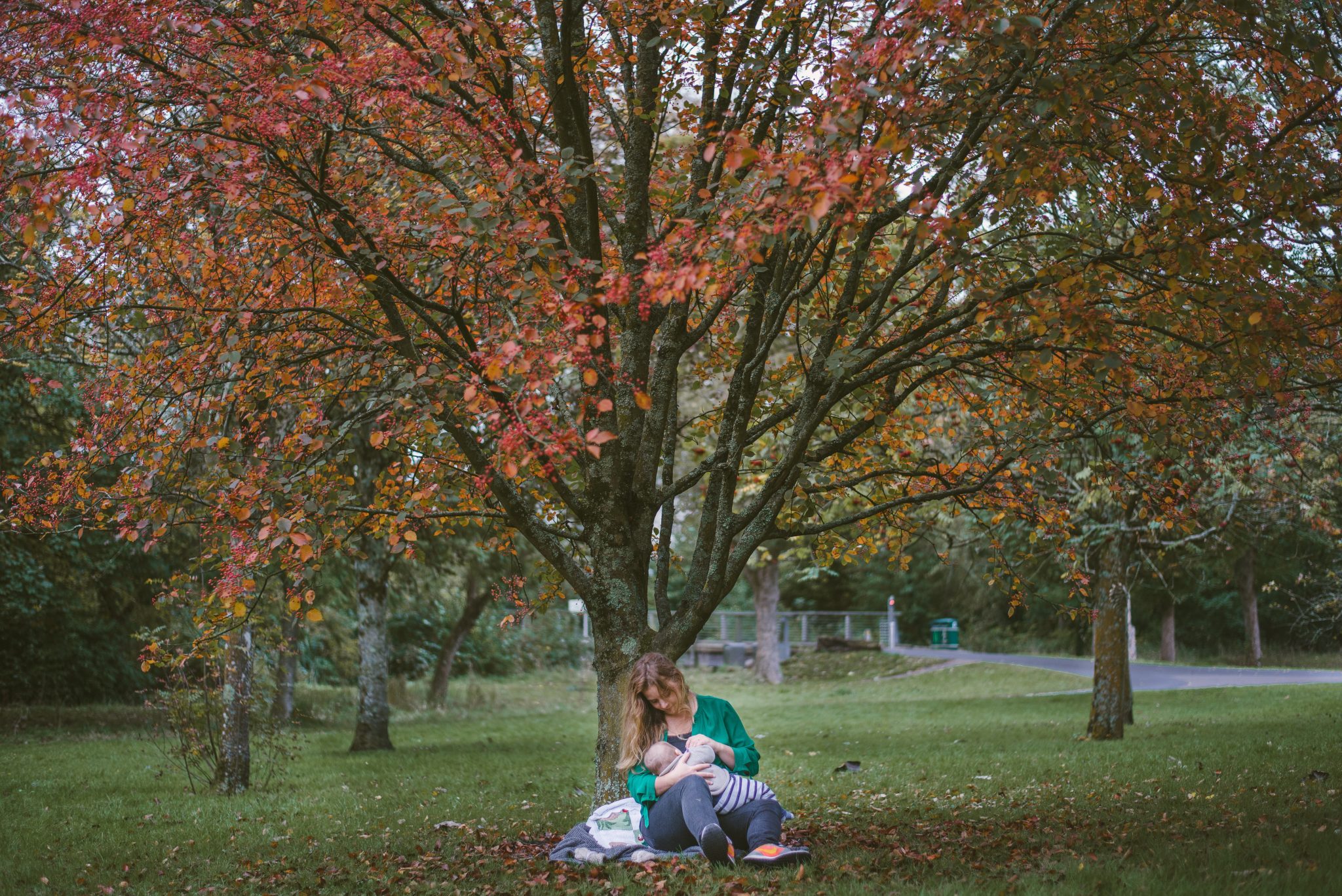 Woman and child under autumn tree in park